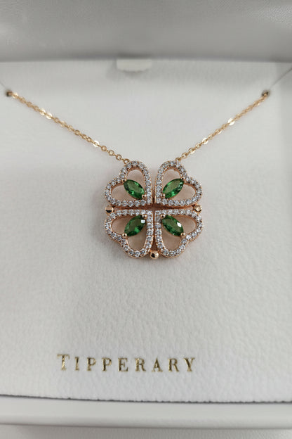 A gold-tone four-leaf clover pendant necklace with light green marquise-cut gemstones and small clear stones, displayed on a white Tipperary jewelry box.